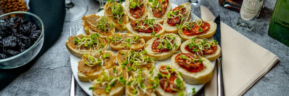 A gourmet appetizer platter featuring delicious bruschetta with sprouts, paired with a selection of wines.